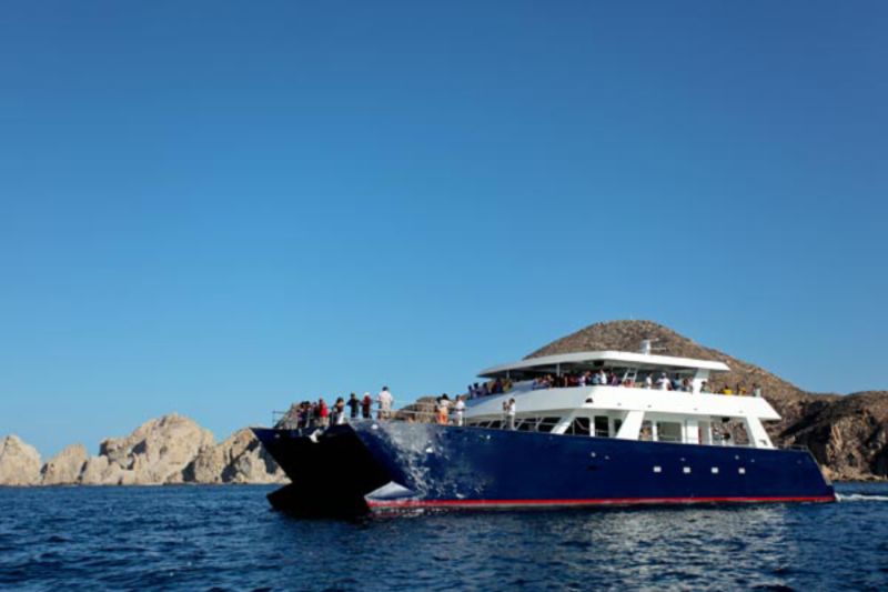 100-foot party catamaran with a navy hull cruising near Land's End