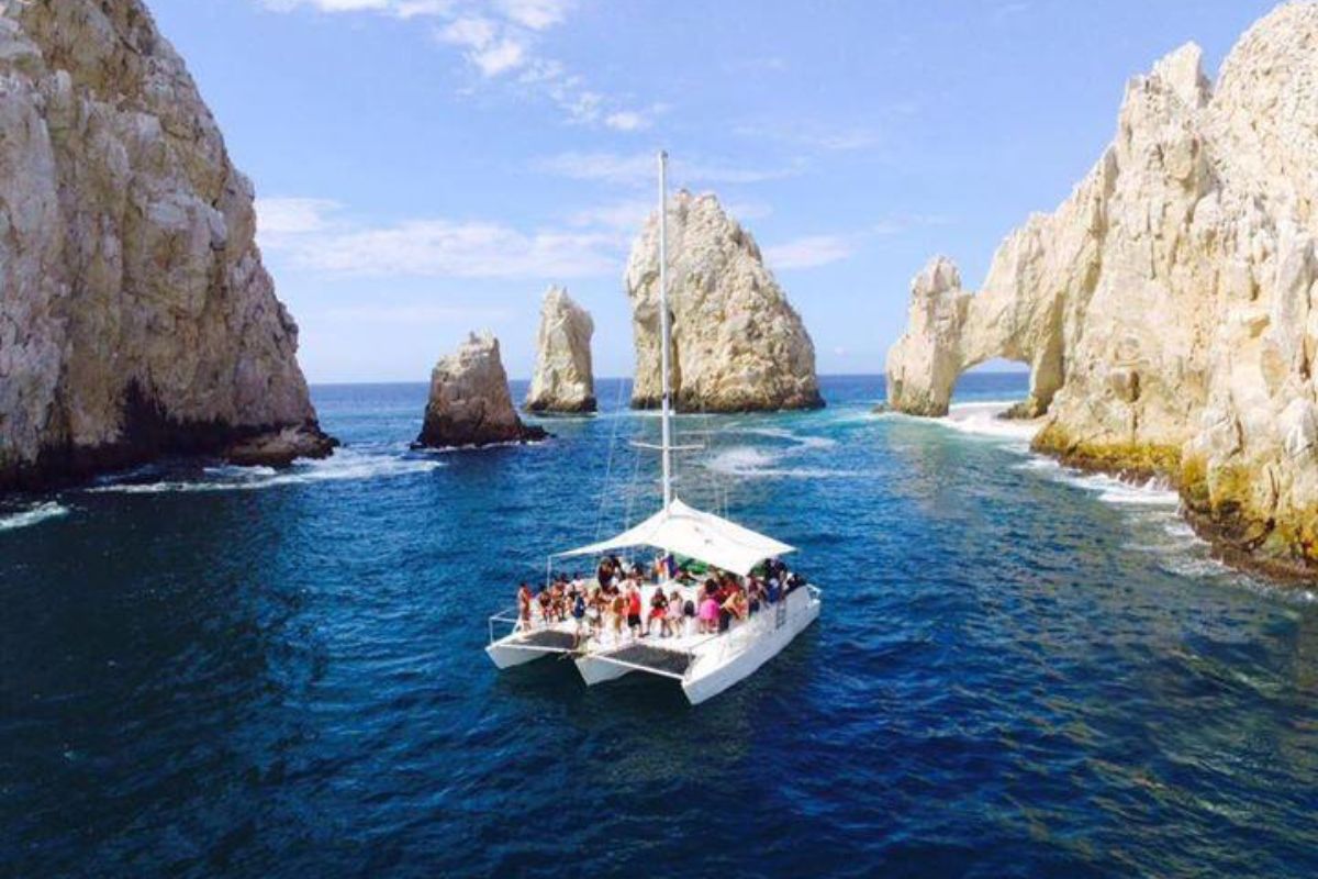 Small sailing trimaran passing between the granite pinnacles of El Arco