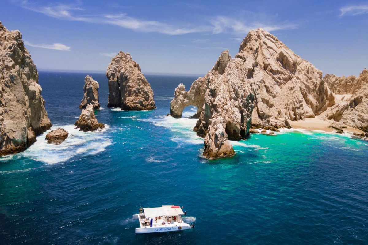 Aerial view of El Arco and the granite pinnacles of Land's End with a catamaran in turquoise water