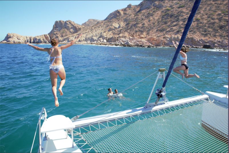 Guest leaping from a catamaran into clear water off the Cabo coastline