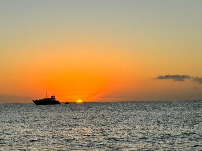 Motor yacht silhouetted against an orange sunset over the Pacific