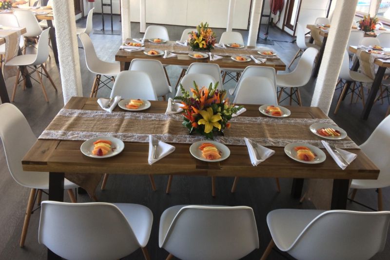 Long banquet tables set with flowers and place settings inside an event catamaran